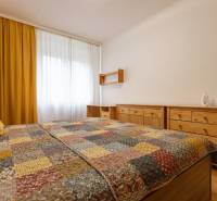 2-izbový byt s balkónom, Ružinov – Ostredky - Spálňa v 2-izbovom byte so žltými závesmi a nábytkom z dreva.