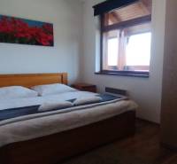 Predaj !Elegantný byt s wellness prvkami pri Jasnej - Spálňa s manželskou posteľou, obrazom kvetov a skriňou v 2-izbovom byte.