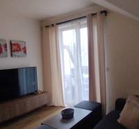 Predaj !Elegantný byt s wellness prvkami pri Jasnej - Obývacia izba v 2-izbovom byte s podlahou s dreveným dekorom, dekoráciou a televízorom.