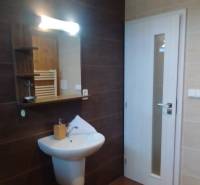 Predaj !Elegantný byt s wellness prvkami pri Jasnej - Kúpeľňa v 2-izbovom byte s umývadlom, zrkadlom a svetlými obkladmi.