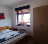 Predaj !Elegantný byt s wellness prvkami pri Jasnej - Spálňa s manželskou posteľou, podlahou s dreveným dekorom a šatníkovou skriňou v 2-izbovom byte.