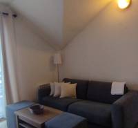 Predaj !Elegantný byt s wellness prvkami pri Jasnej - Obývacia izba v 2-izbovom byte s pohovkou, kávovým stolom a presklenými dverami na balkón.