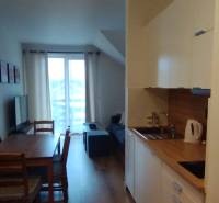 Predaj !Elegantný byt s wellness prvkami pri Jasnej - Kuchynský kút a jedálenský stôl so stoličkami, 2-izbový byt, podlaha s dreveným dekorom.