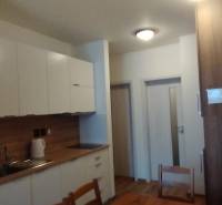 Predaj !Elegantný byt s wellness prvkami pri Jasnej - Kuchyňa v 2-izbovom byte s podlahou s dreveným dekorom a bielymi skriňami.