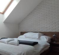 Predaj !Elegantný byt s wellness prvkami pri Jasnej - Spálňa v 2-izbovom byte s posteľou, strešným oknom a tehlovým obkladom.