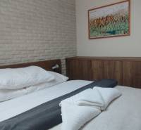 Predaj !Elegantný byt s wellness prvkami pri Jasnej - Spálňa v 2-izbovom byte s posteľou a skriňou, podlaha s dreveným dekorom.