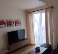 Predaj !Elegantný byt s wellness prvkami pri Jasnej - Obývacia izba s pohovkou, televízorom a červenými obrazmi v 2-izbovom byte.