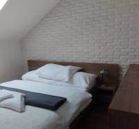 Predaj !Elegantný byt s wellness prvkami pri Jasnej - Spálňa s posteľou a strešným oknom v 2-izbovom byte s dekoratívnym tehlovým obkladom.