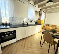 - PRENÁJOM - 3 IZBOVÝ BYT - WILSONOVA UL. - STARÉ MESTO - Kuchyňa s bielymi skrinkami, farebnou chladničkou a podlahou s dreveným dekorom.