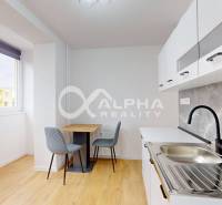 Prenájom 1 izbový byt s loggiou, centrum, Spišská Nová Ves - Kuchyňa v 1-izbovom byte s podlahou s dreveným dekorom a jedálenským stolom.