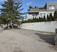 Parkovacie státie v Ružinove – pri Gymnáziu I. Horvátha a električke - Garáže na Vavrínovej ulici v Bratislave - Ružinove s okolitou zeleňou a domami.