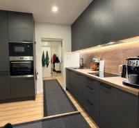 KOMPLETNE prerobený 4i byt s balkónom, 77m2 - ZÁTVOR - Kuchyňa v 4-izbovom byte s tmavými skriňami a podlahou s dreveným dekorom.