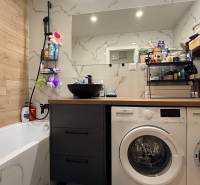 KOMPLETNE prerobený 4i byt s balkónom, 77m2 - ZÁTVOR - Kúpeľňa so sprchou a práčkou v 4-izbovom byte, podlaha s dreveným dekorom.