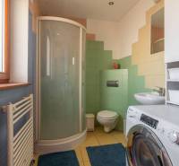 Predaj priestranného rodinného domu v historickej časti Popradu  - Kúpeľňa v rodinnom dome s práčkou, sprchovým kútom a farebnými dlaždicami.