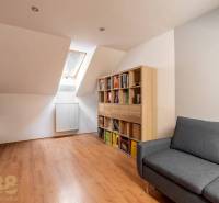 Predaj priestranného rodinného domu v historickej časti Popradu  - Podkrovná izba v rodinnom dome s podlahou s dreveným dekorom a pohodlnou sedačkou.