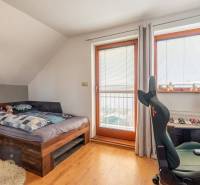 Predaj priestranného rodinného domu v historickej časti Popradu  - Izba s posteľou, pracovným stolom a stoličkou; podlaha s dreveným dekorom.