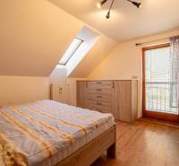 Predaj priestranného rodinného domu v historickej časti Popradu  - Spálňa s podlahou s dreveným dekorom a strešným oknom v rodinnom dome.