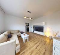 REZERVOVANÉ !!!  EXKLUZÍVNE: Štýlový 2,5-izbový byt s panoramatickým v - Obývačka s podlahou s dreveným dekorom v 3-izbovom byte so svetlou sedačkou a TV skrinkou.