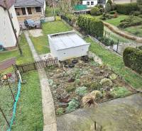 RODINNÝ DOM - HORNÉ OZOROVCE-POZEMOK 566 m2- 3,5 IZBOVÝ/ GARÁŽ - Rodinný dom v Horných Ozorovciach, Bánovce nad Bebravou, ukazuje záhradu so záhonom a garážou.