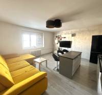 Prenájom pekný 2 izbový byt Šancová ulica, Bratislava III. Nové Mesto - Obývacia izba s veľkou žltou sedačkou, kuchynským ostrovom a televíziou v 2-izbovom byte.