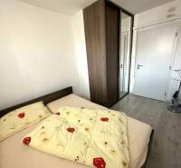 Prenájom pekný 2 izbový byt Šancová ulica, Bratislava III. Nové Mesto - Spálňa v 2-izbovom byte s posteľou, vstavanou skriňou a podlahou s dreveným dekorom.