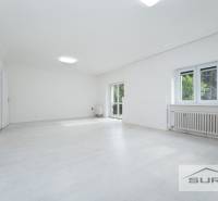 PRENÁJOM 4-IZBOVÉHO BYTU | ZÁHRADA | DVOJGARÁŽ | KRČMÉRYHO ULICA - Priestranná obývacia izba v 4-izbovom byte s bielou podlahou a veľkými oknami.