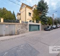 PRENÁJOM 4-IZBOVÉHO BYTU | ZÁHRADA | DVOJGARÁŽ | KRČMÉRYHO ULICA - Ulica Krčméryho v Bratislave - Staré Mesto s garážovým vjazdom a zaparkovanými autami.