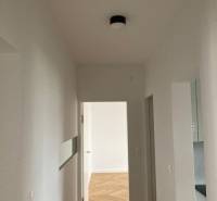 Predaj 2 izbového bytu, Drotárska cesta, Bratislava - Chodba v 2-izbovom byte s podlahou s dreveným dekorom a bielymi stenami.