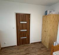1-izbový byt na prenájom v Hliníku nad Hronom - Izba s dreveným dekorom, drevenými skriňami a posteľou v 1-izbovom byte.