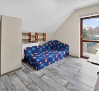 Rodinný dom s veľkým pozemkom a priestorom na podnikanie – T.Jastrabie - Podkrovná izba v rodinnom dome s farebnou pohovkou a výhľadom do záhrady.