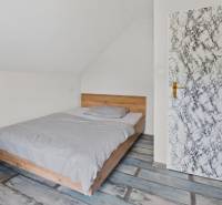 Rodinný dom s veľkým pozemkom a priestorom na podnikanie – T.Jastrabie - Spálňa v rodinnom dome s posteľou, radiátorom a dverami s mramorovým dekorom.