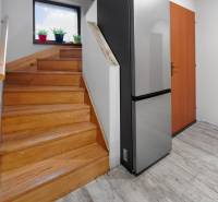 Rodinný dom s veľkým pozemkom a priestorom na podnikanie – T.Jastrabie - Drevené schody a chladnička s dreveným dekorom podlahy v rodinnom dome.