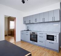 NA PREDAJ-3-izbový byt s loggiou a výhľadom na centrum mesta, KE-JUH - Kuchyňa v 3-izbovom byte s modernými spotrebičmi a podlahou s dreveným dekorom.