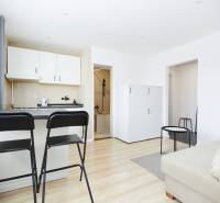 NA PREDAJ,2-IZBOVÝ TEHLOVÝ BYT,KOŠICE-SEVER,LOMNICKÁ UL. - Interiér 2-izbového bytu s kuchyňou, barovými stoličkami a podlahou s dreveným dekorom.