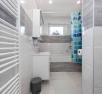 NOVOSTAVBA BUNGALOVU S MNOŽSTVOM PRIESTORU, v slepej ulici, Pružina - Kúpeľňa v rodinnom dome s bielymi a sivými obkladmi a sprchovým závesom.