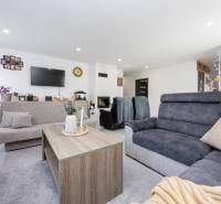 NOVOSTAVBA BUNGALOVU S MNOŽSTVOM PRIESTORU, v slepej ulici, Pružina - Obývačka v rodinnom dome s pohodlnými sedačkami a dekoráciami vrátane krbu.