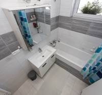 NOVOSTAVBA BUNGALOVU S MNOŽSTVOM PRIESTORU, v slepej ulici, Pružina - Kúpeľňa s vaňou a umývadlom, rodinný dom. Kachličky v šedých tónoch.