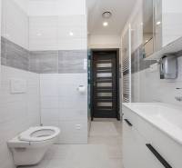 NOVOSTAVBA BUNGALOVU S MNOŽSTVOM PRIESTORU, v slepej ulici, Pružina - Kúpeľňa v rodinnom dome s bielou sanitou a sivými obkladmi.