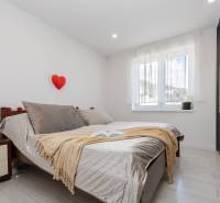 NOVOSTAVBA BUNGALOVU S MNOŽSTVOM PRIESTORU, v slepej ulici, Pružina - Svetlá spálňa s posteľou, skriňou a oknom, podlaha s dreveným dekorom.