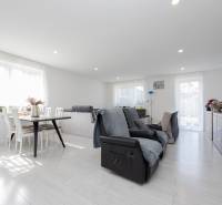 NOVOSTAVBA BUNGALOVU S MNOŽSTVOM PRIESTORU, v slepej ulici, Pružina - Moderná obývačka s pohodlnými kreslami a jedálenským stolom v rodinnom dome.