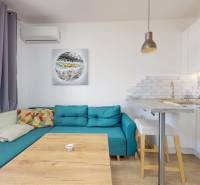 Pekný 2-izbový byt s lodžiou | investičná príležitosť | - Obývacia izba v 2-izbovom byte s pohovkou a kuchynským kútom s podlahou s dreveným dekorom.