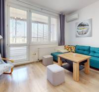 Pekný 2-izbový byt s lodžiou | investičná príležitosť | - Obývacia izba v 2-izbovom byte s podlahou s dreveným dekorom a modrou sedačkou.