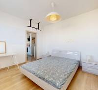 Pekný 2-izbový byt s lodžiou | investičná príležitosť | - Spálňa v 2-izbovom byte s posteľou, stolíkom a podlahou s dreveným dekorom.