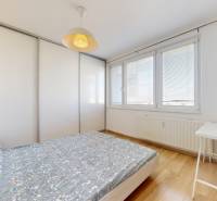 Pekný 2-izbový byt s lodžiou | investičná príležitosť | - Spálňa v 2-izbovom byte s posteľou, stolíkom a podlahou s dreveným dekorom.