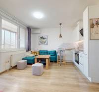 Pekný 2-izbový byt s lodžiou | investičná príležitosť | - Obývacia izba s kuchyňou, podlahou s dreveným dekorom, sedačkou v 2-izbovom byte.