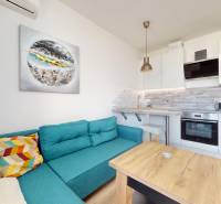 Pekný 2-izbový byt s lodžiou | investičná príležitosť | - Obývacia izba spojená s kuchynským kútom, tyrkysová sedačka, podlaha s dreveným dekorom.