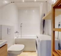 Pekný 2-izbový byt s lodžiou | investičná príležitosť | - Kúpeľňa s vaňou, práčkou a policou v 2-izbovom byte, podlaha s dreveným dekorom.