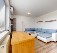 | Priestranný 2,5-izb. byt s walk-in šatníkom | parkovanie | - Obývačka v 2-izbovom byte s podlahou s dreveným dekorom a veľkou sedačkou.