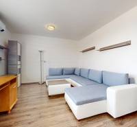 | Priestranný 2,5-izb. byt s walk-in šatníkom | parkovanie | - Obývačka v 2-izbovom byte s rohovou sedačkou a podlahou s dreveným dekorom.