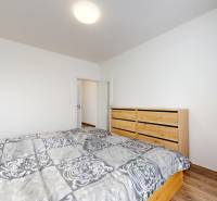 | Priestranný 2,5-izb. byt s walk-in šatníkom | parkovanie | - Spálňa v 2-izbovom byte s podlahou s dreveným dekorom a štýlovou posteľou.